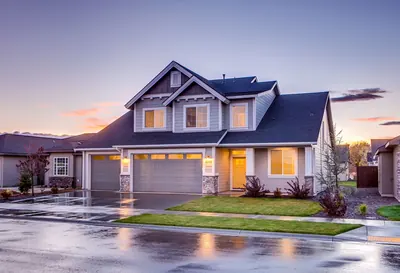 Suburban home at twilight with a wet driveway and lit windows